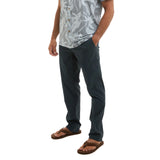 Person wearing dark pants and a patterned shirt on a white background