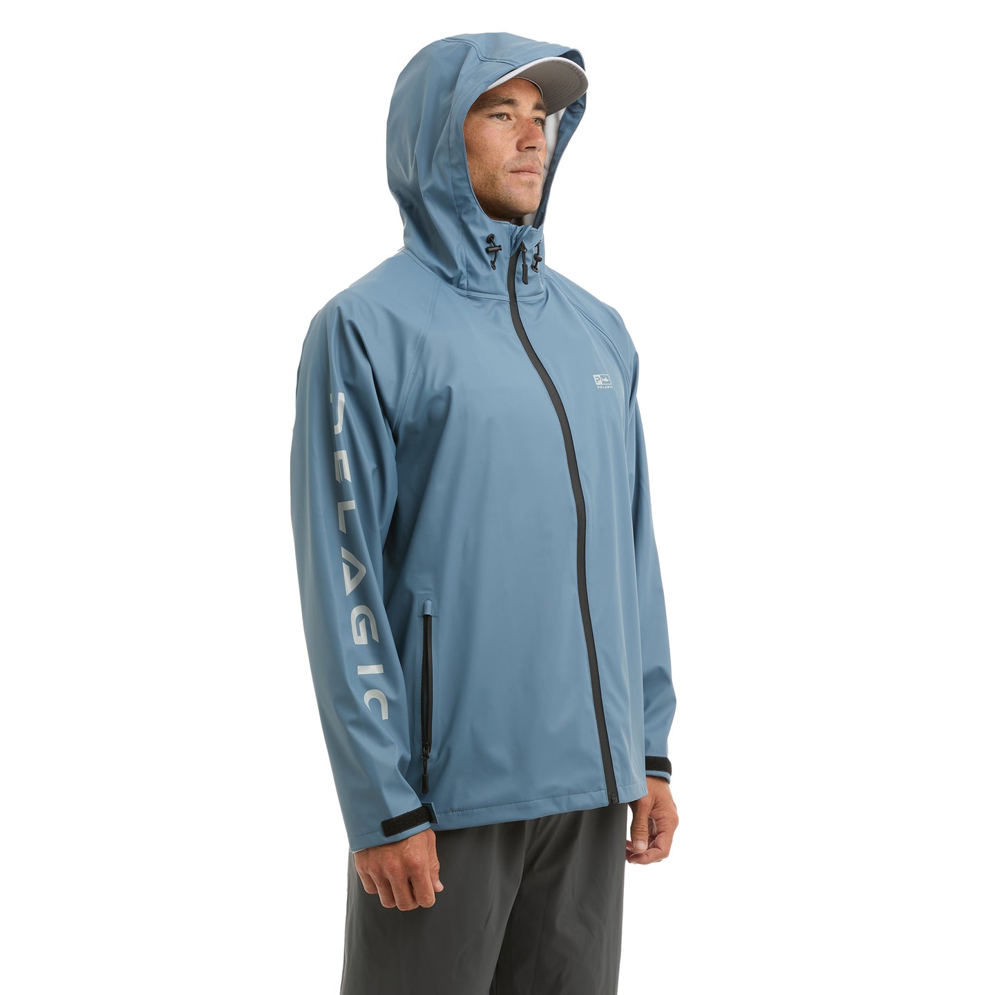 Person wearing a blue Pelagic rain jacket with a hood on a white background