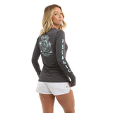 Woman wearing a grey long-sleeve fishing shirt with Pelagic branding on the back.