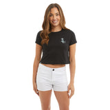 Woman wearing a black t-shirt with a logo and white shorts on a white background