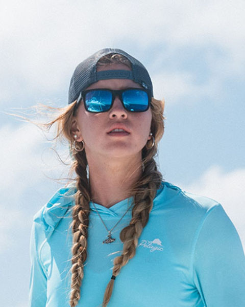 Person wearing a blue cap and sunglasses with a clear sky background