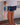 Person wearing navy shorts with fish pattern holding a colorful fishing lure.